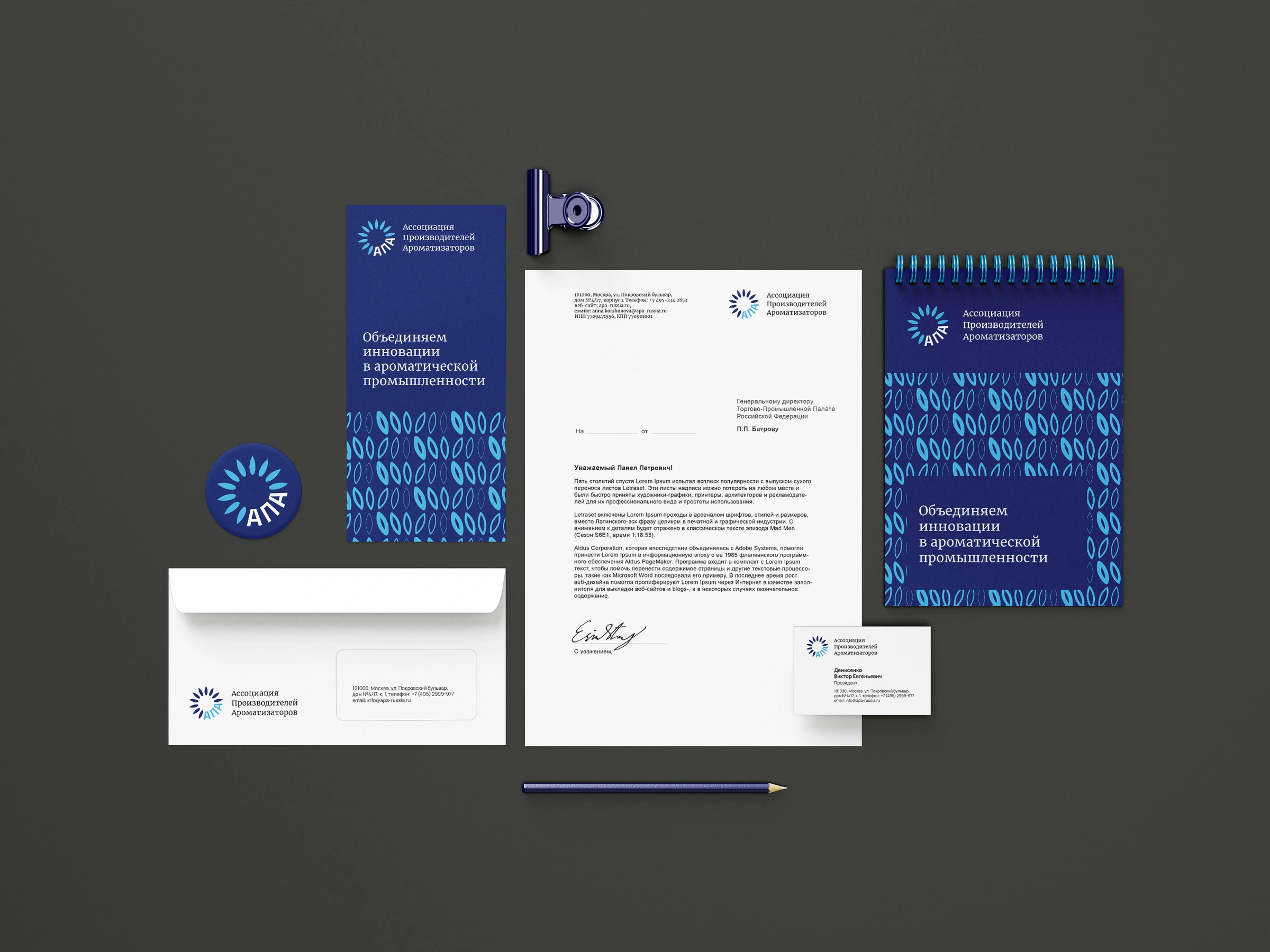 Complete original APA stationery system on a dark surface: folder, notebook, letterhead, envelope, cards and pencil